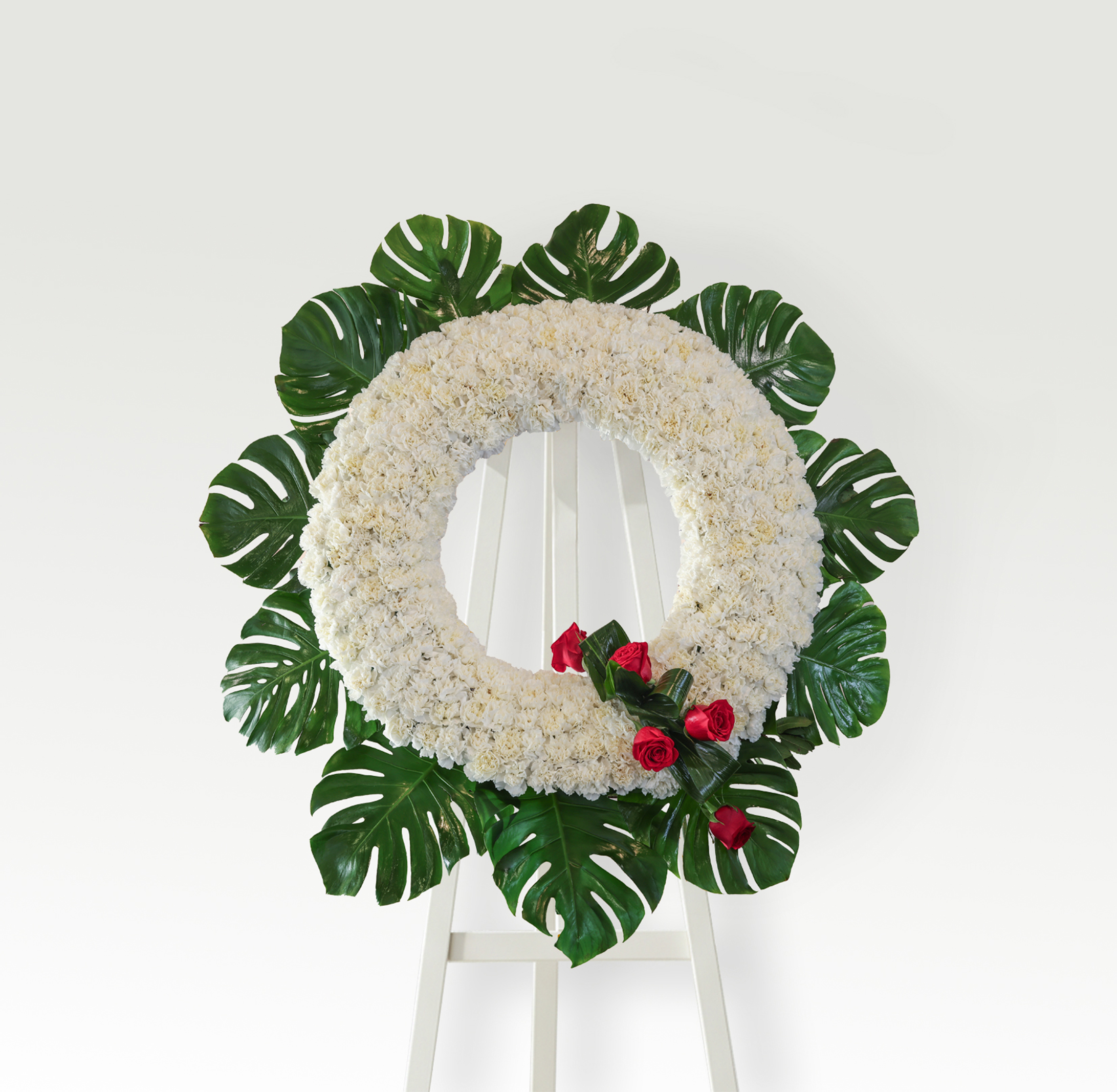 Corona de clavel blanco con detalle de rosas rojas