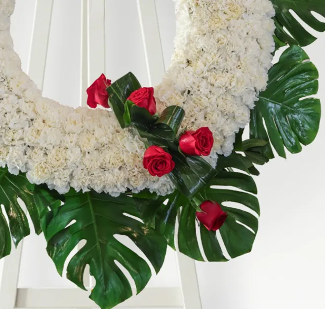 Corona de clavel blanco con detalle de rosas rojas