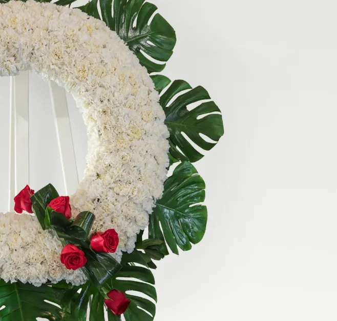 Corona de clavel blanco con detalle de rosas rojas